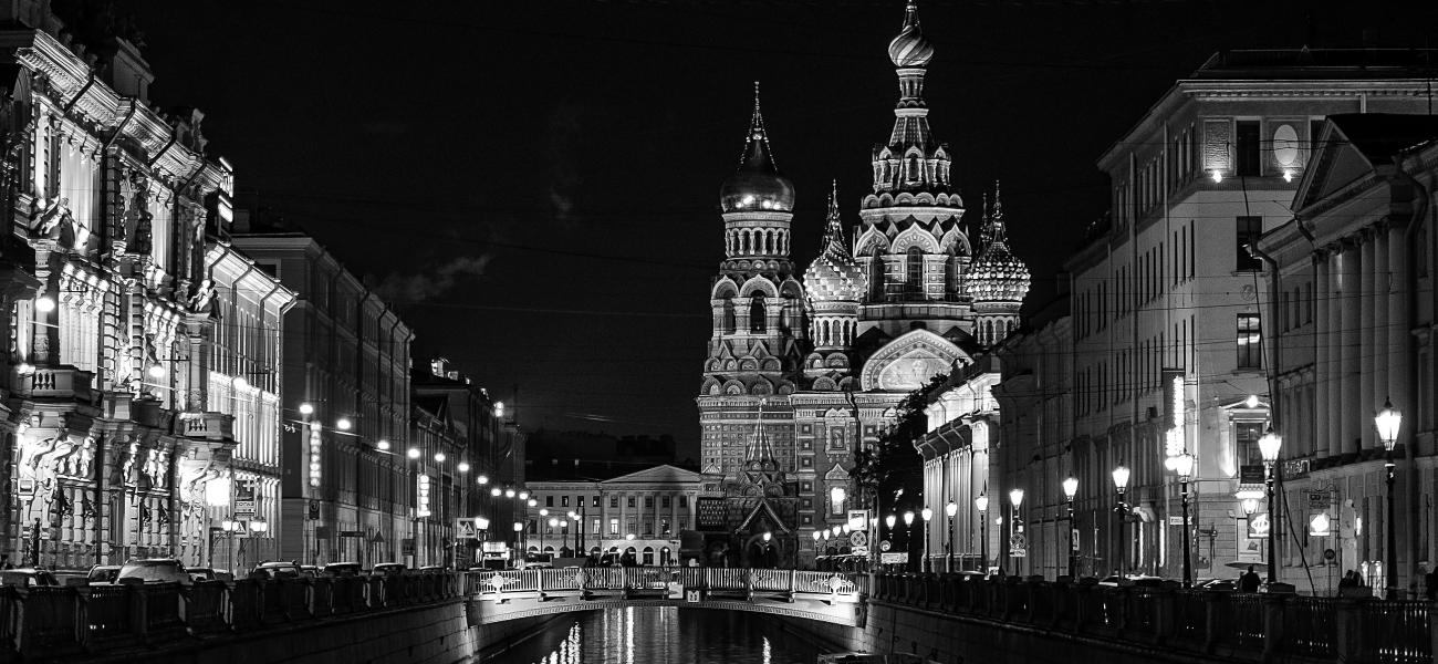 St. Petersburg, Russia at night, black and white view of a building-lined canal and a church. 