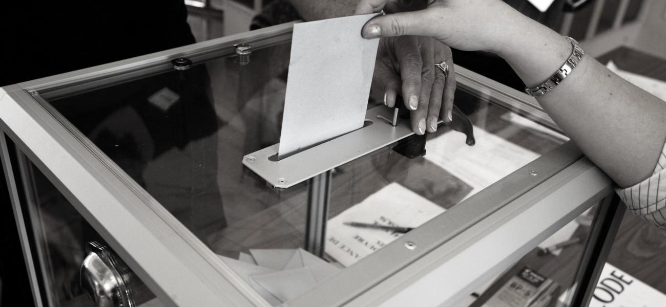 Hand dropping ballot in ballot box.