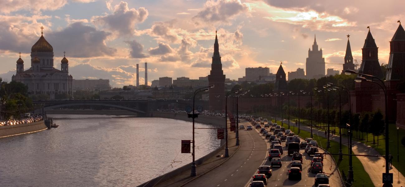 Moscow traffic alongside the Moskva River as the sun sets behind the Kremlin.